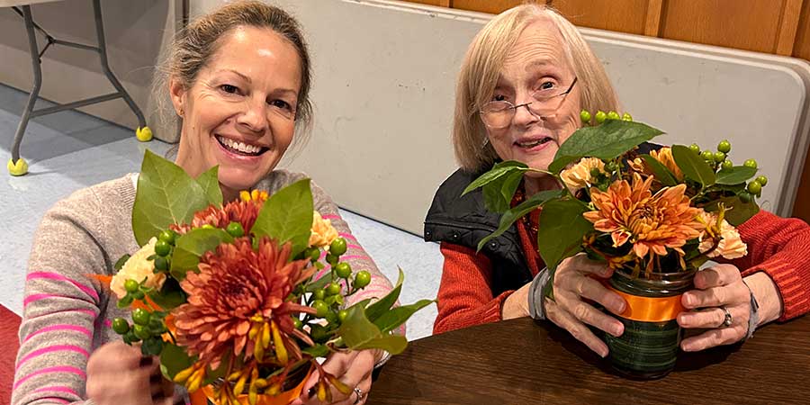 Two women at table with potted flowers